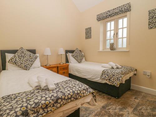 1 dormitorio con 2 camas y ventana en Apple Tree Cottage, en Dunnington