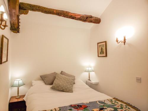 a bedroom with a bed with white sheets and two lamps at Farrier's Cottage in Sedbergh