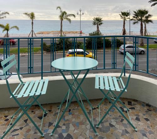 d'une table et de deux chaises sur un balcon donnant sur l'océan. dans l'établissement PALAIS ELISABETH PROMENADE DES ANGLAIS, à Nice