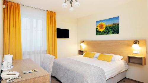 リガにあるHestia Hotel Draugiのベッドとテーブルが備わるホテルルームです。
