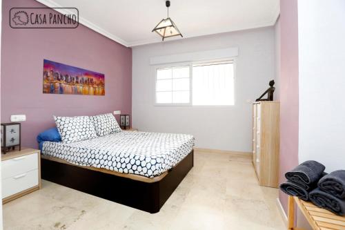 ein Schlafzimmer mit einem Bett und einer rosa Wand in der Unterkunft Apartamento Milla de oro 5 Personas in Marbella