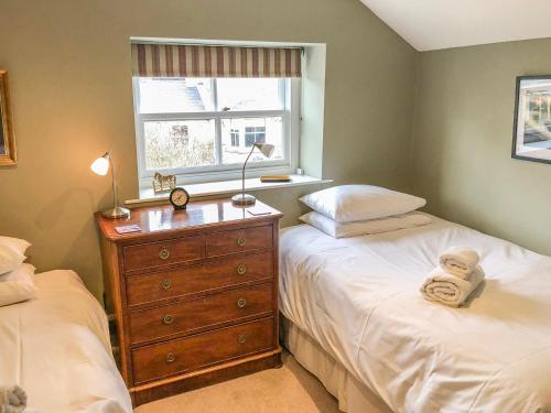 a bedroom with two beds and a dresser with a window at The Granary in Appleton le Moors