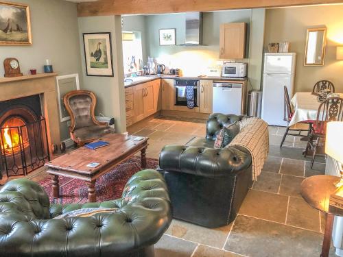 a living room with two leather couches and a kitchen at The Granary in Appleton le Moors