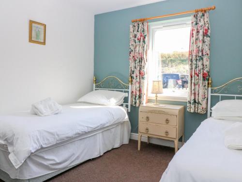 two beds in a room with a window at Driftwood Cottage in Craignure
