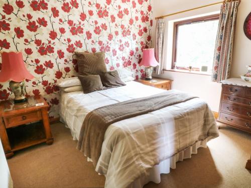 a bedroom with a bed with red floral wallpaper at Woodlands in Halton West