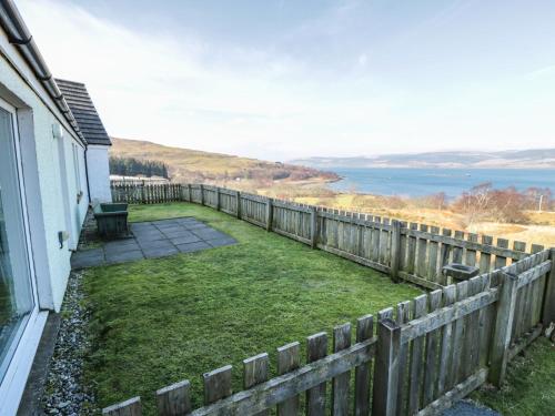 a backyard with a fence and a lawn with a view at Starfish Cottage in Craignure