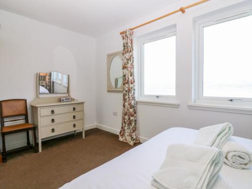 a bedroom with a bed and a dresser and two windows at Starfish Cottage in Craignure