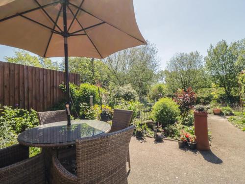 a table and chairs with an umbrella in a garden at Kingfisher in Wattisfield