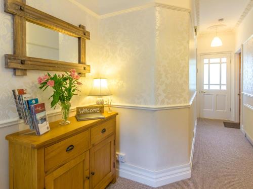 a room with a dresser with a mirror and a vase of flowers at Estuary View in Warkworth