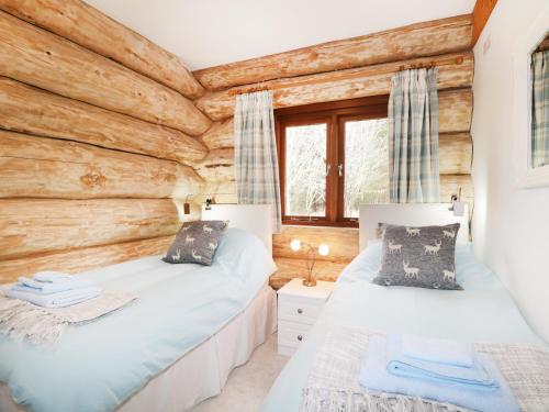 a bedroom with two beds in a log cabin at Heron Lodge in Inverness