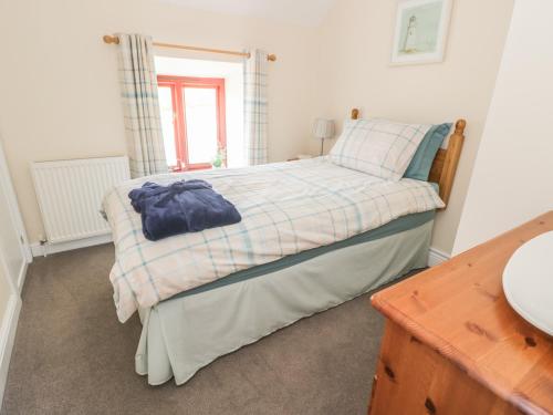 a bedroom with a bed with a blue shirt on it at Oak Cottage in Llandysul