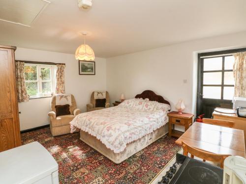 1 dormitorio con 1 cama y 2 sillas en The Old Workshop, en Knowstone