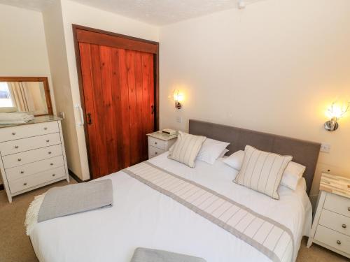 BeaworthyにあるWagtailの白いベッド2台と木製のドアが備わるベッドルーム1室が備わります。