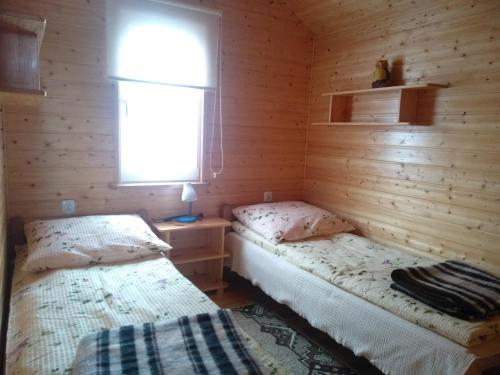 two beds in a log cabin with a window at Domki pod Żukowcem in Solina
