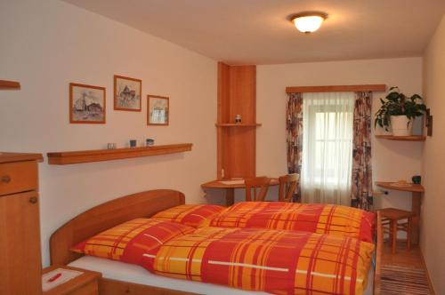 een slaapkamer met een bed met een rode en gele deken bij Bauernhof Mittereibenberger in Liebenau