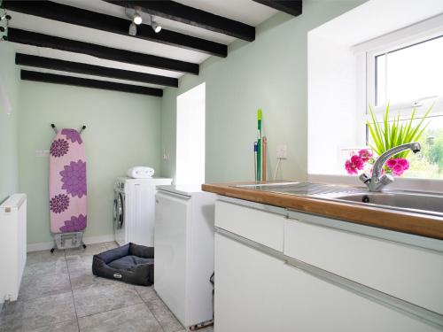 a kitchen with white cabinets and a sink and a window at 3 Horse Pool Road in Laugharne