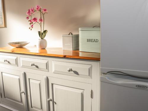 a kitchen counter with white cabinets and flowers on it at The Hay Loft in Craven Arms