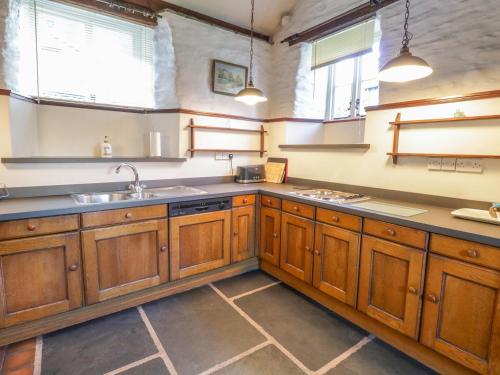 a large kitchen with wooden cabinets and a sink at Mill Cottage in Staveley