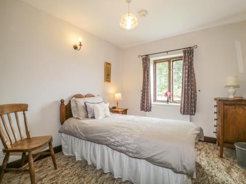 ein Schlafzimmer mit einem Bett, einem Stuhl und einem Fenster in der Unterkunft Stonegarth Cottage in Penrith