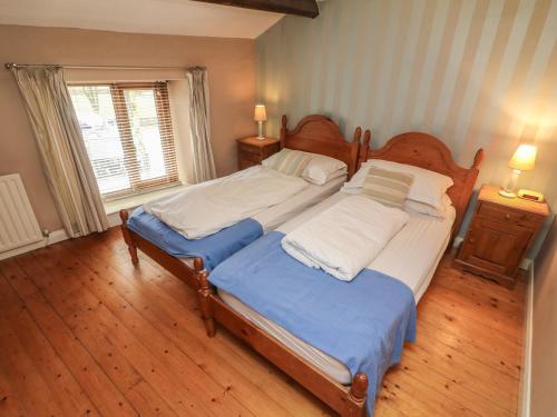 a bedroom with a large bed and a window at Puddle Duck Cottage in Spark Bridge