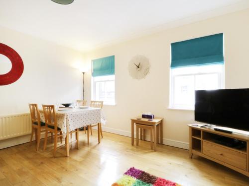 a dining room with a table and chairs and a television at Fox's Den in Keswick