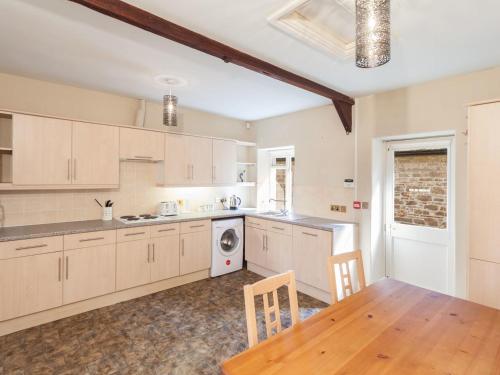 a kitchen with white cabinets and a wooden table at Great Bidlake Manor in Bridestowe