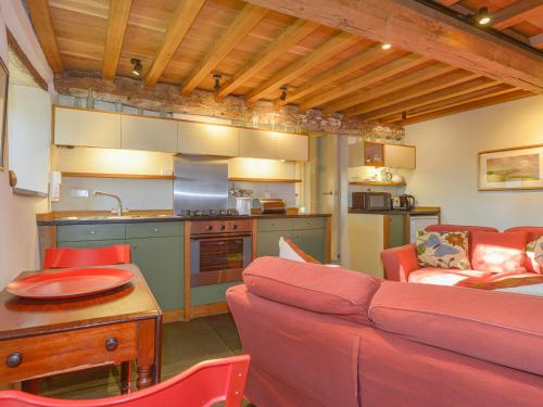 a living room with a red couch and a kitchen at The Bakehouse in Gidleigh