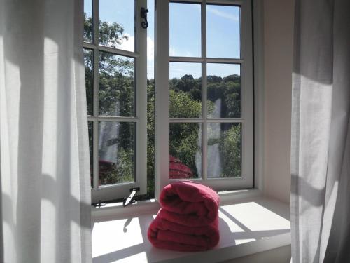 a red towel is sitting on a window sill at Barn Cottage in Hawkridge