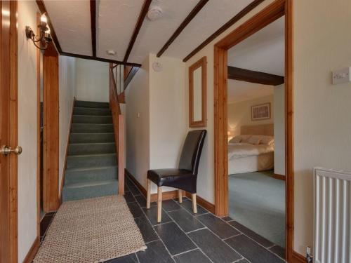 a room with a staircase and a bed and a chair at Owls Roost in Kentisbury