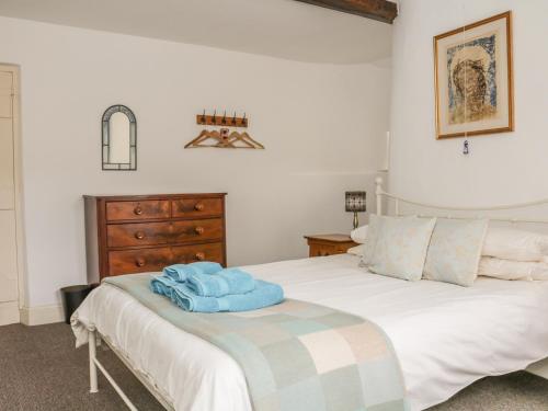 a bedroom with a white bed with a wooden dresser at Alice Cottage in Minehead