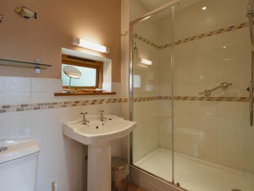 uma casa de banho com um lavatório e um chuveiro em 1 Shippen Cottages em Cotleigh