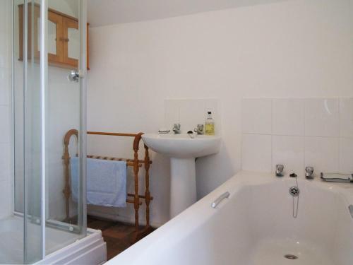 a bathroom with a bath tub and a sink at Heyden Cottage in Minehead