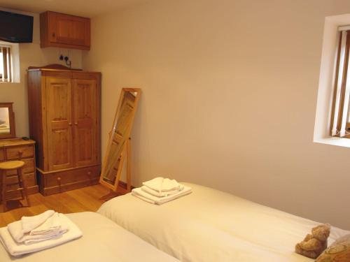 a bedroom with two beds and a dresser and a mirror at Hiscox Cottage in Southleigh