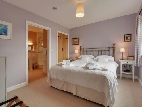 um quarto com uma cama com lençóis brancos e almofadas em 1 Shippen Cottages em Cotleigh