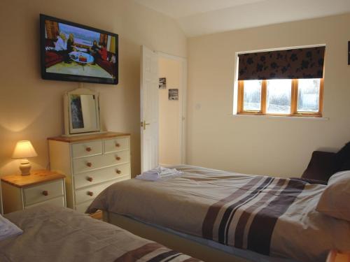 a bedroom with two beds and a tv on the wall at Barn View in Welcombe