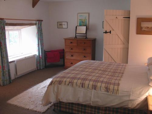 a bedroom with a bed and a dresser and a door at Tom in Bodmin