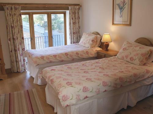 Duas camas num quarto com uma janela em The Hay Barn em Halwell
