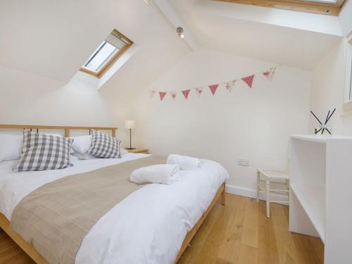 a white bedroom with a large bed with pillows at Torrings Barn in Kingsbridge
