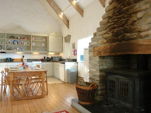 a kitchen with a stone fireplace and a table and a dining room at Harry in Bodmin