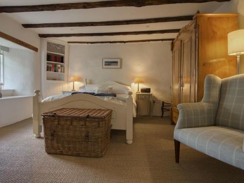 een slaapkamer met een bed, een stoel en een bank bij Cherry Tree Cottage in Noss Mayo