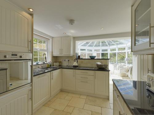 een keuken met witte kasten en een groot raam bij Mays Cottage in Saint Issey