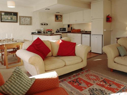 a living room with a couch and a kitchen at Dick Cottage in Bodmin