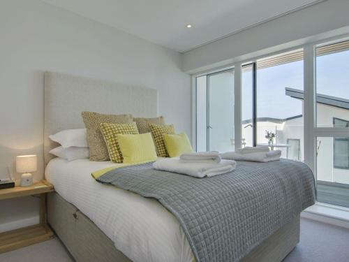 a bedroom with a bed with yellow pillows and a window at Rosen in Crantock