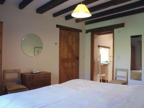 1 dormitorio con cama blanca y puerta de madera en The Clock House en Harford