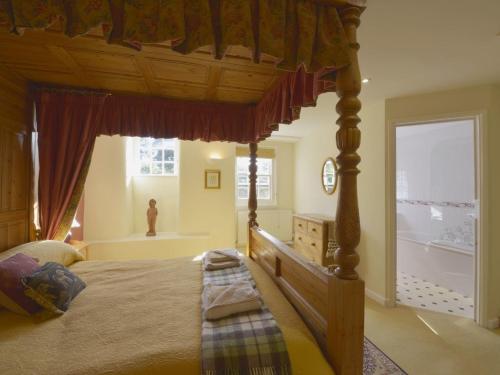 a bedroom with a canopy bed and a window at Grooms Cottage in Saint Minver