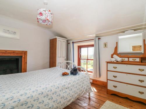 ein Schlafzimmer mit einem Bett, einer Kommode und einem Spiegel in der Unterkunft Uphill Cottage in Saint Ervan