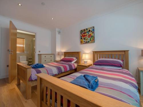 two beds in a room with wooden floors at Neptune in St Merryn