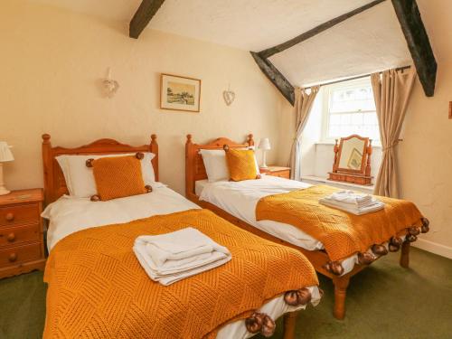a bedroom with two beds with orange blankets and a window at Cousham Cottage in Cawsand
