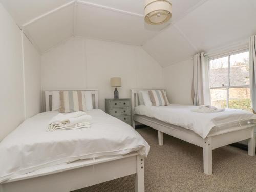 two beds in a white room with a window at Boundys House in St Ives