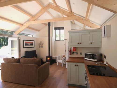 a living room with a couch and a kitchen at Mugwell Barn in Callington